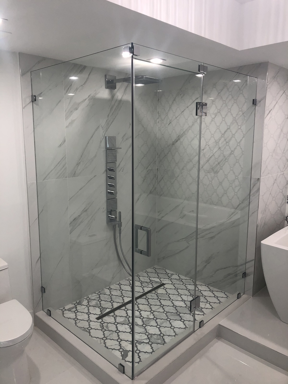 L-shape frameless shower door installed in Miami bathroom chrome hardware